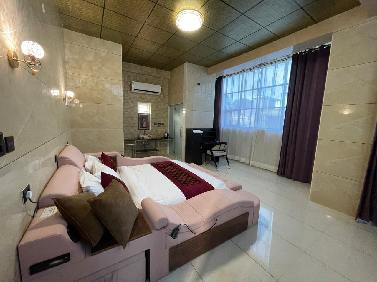 A modern hotel room with a large bed, a desk, and a window with curtains.