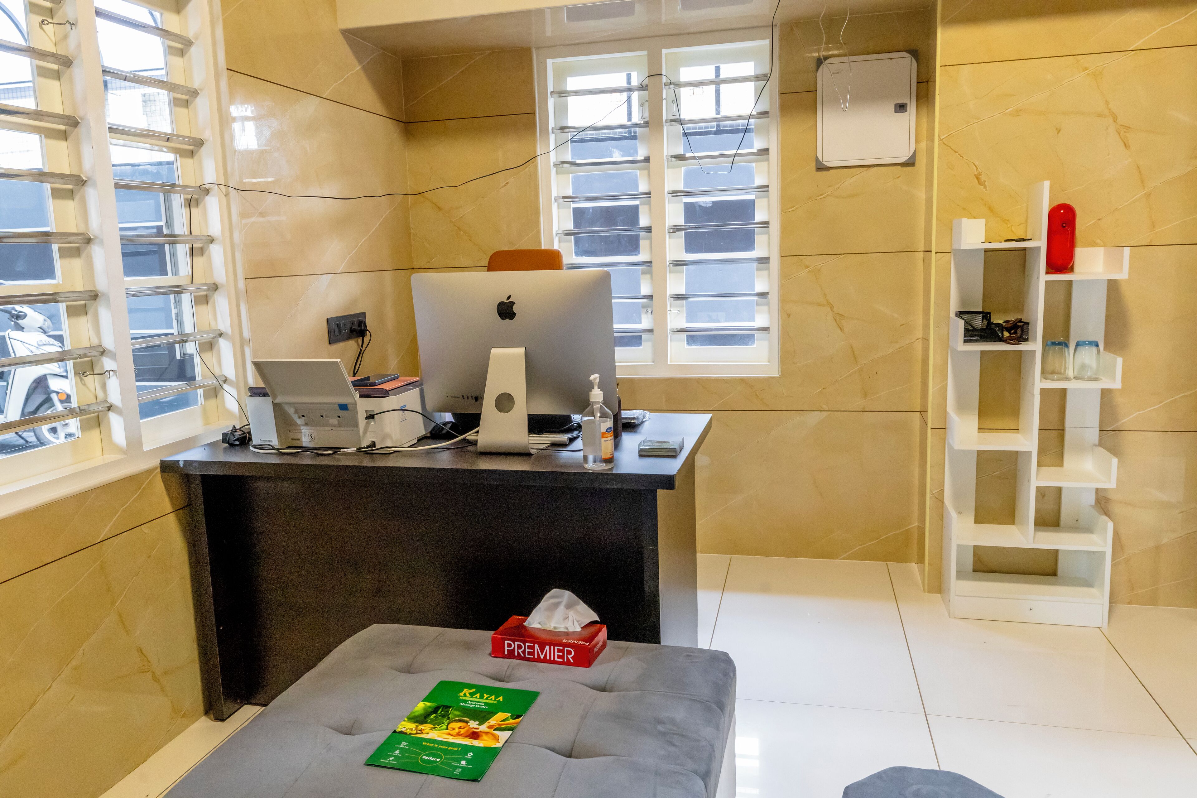 A hotel reception area with a desk, computer, and a window.