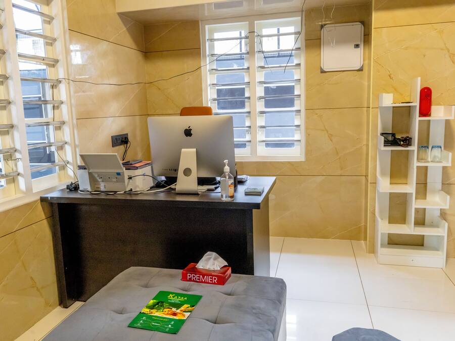 Zona de recepción de un hotel con mostrador, computadora y ventana.