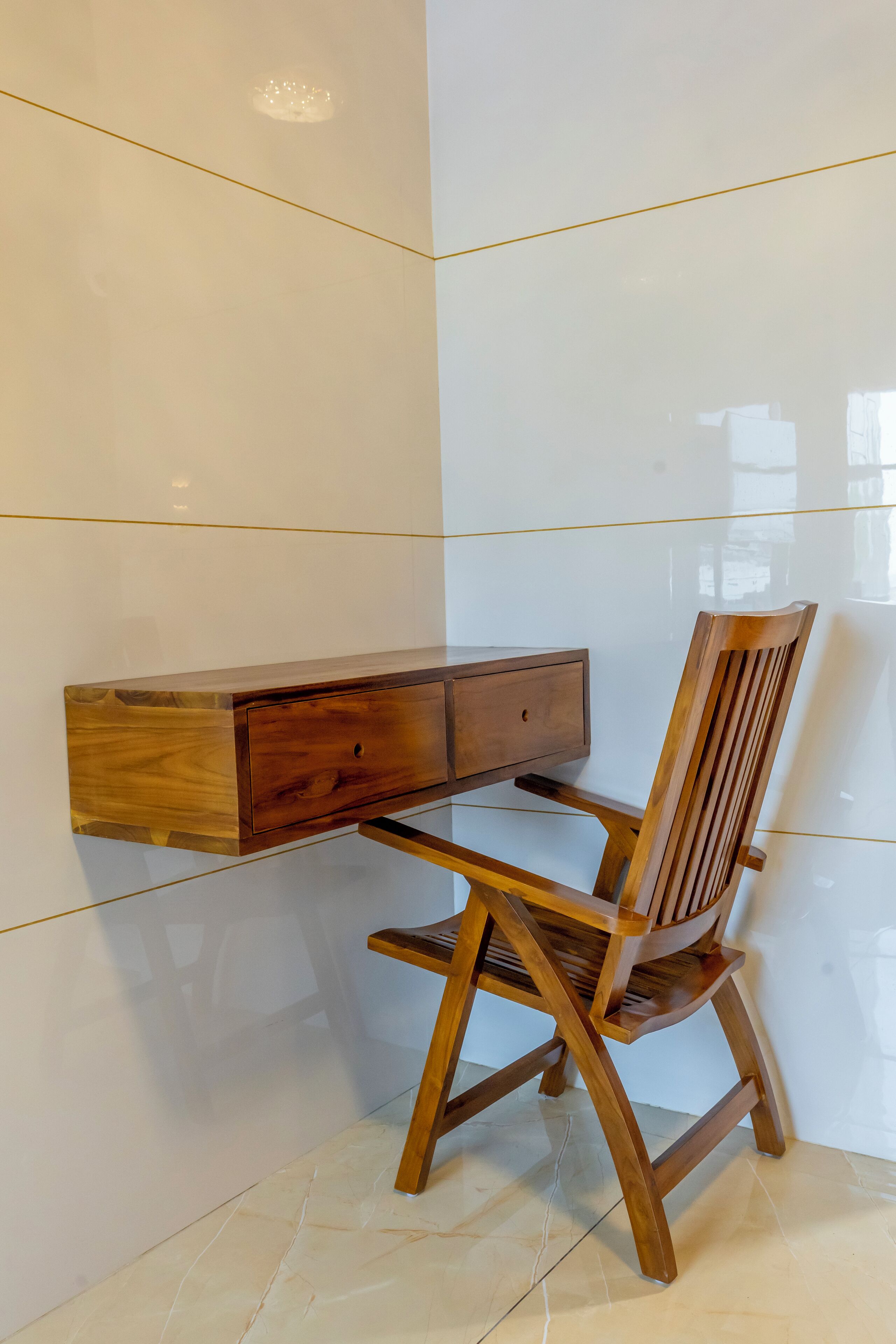 A wooden desk with a drawer unit against a white tiled wall.