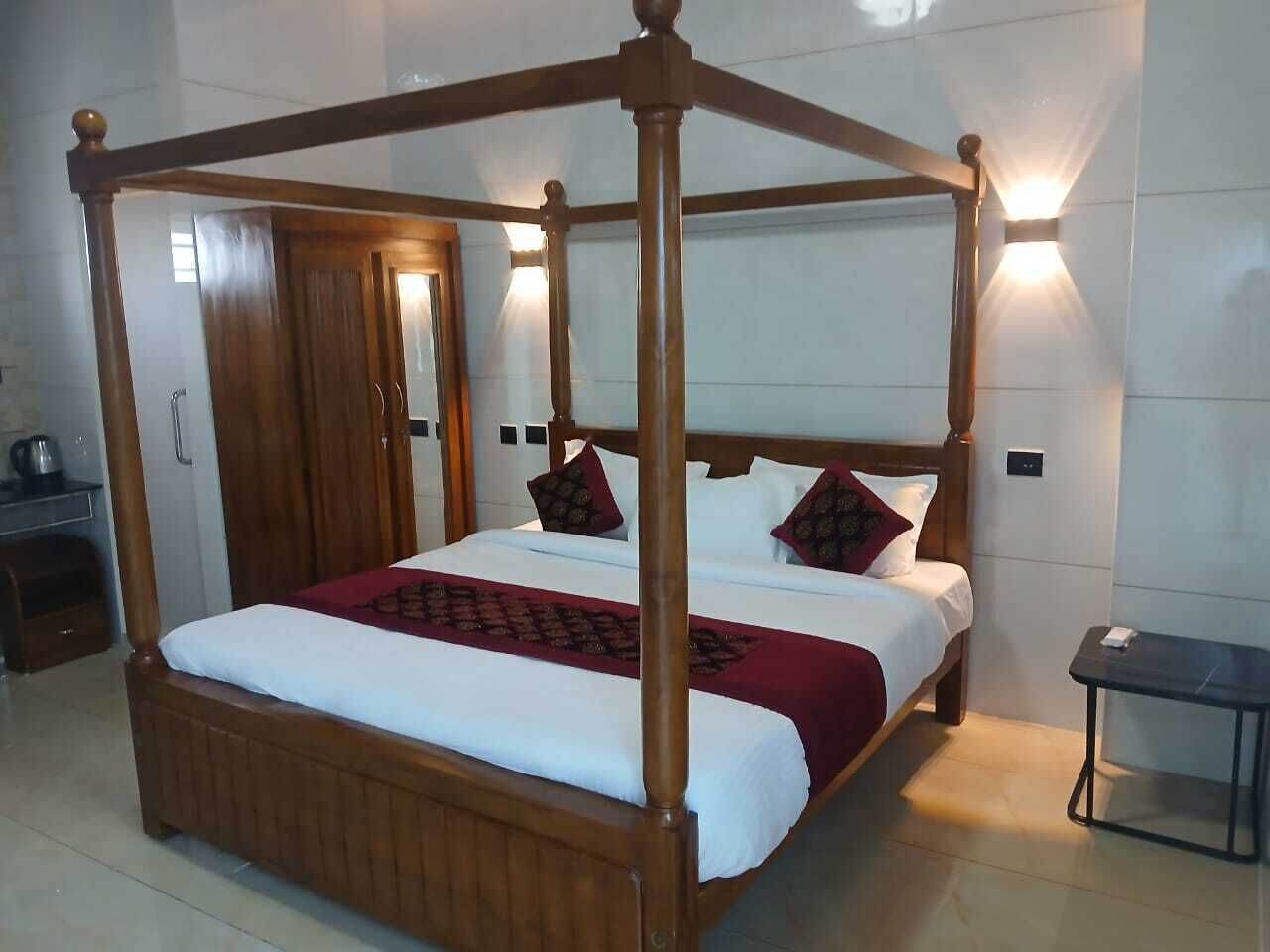 A four-poster bed with a wooden frame, white bedding, and a red throw blanket.