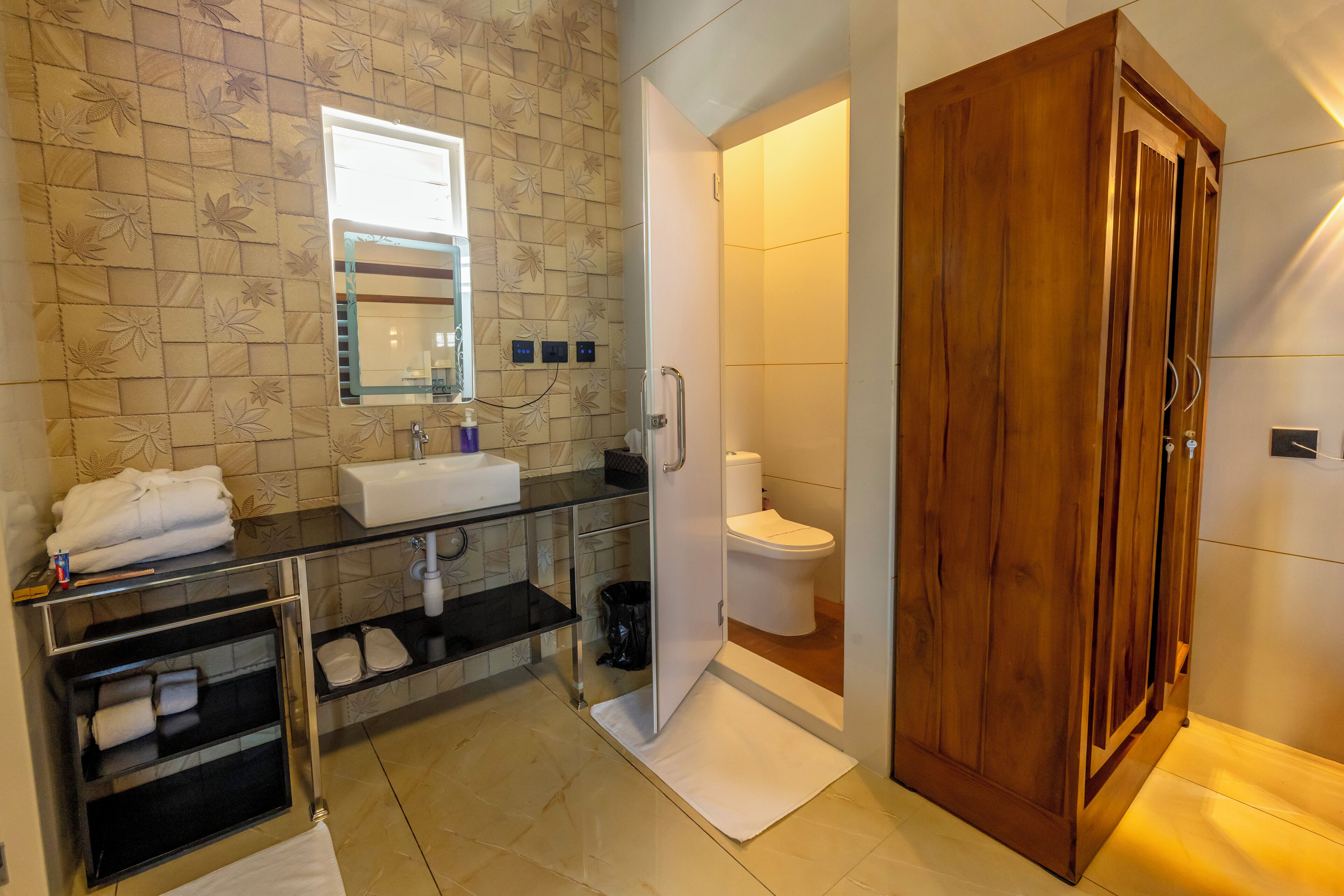 A bathroom with a wooden cabinet, a glass shower enclosure, a sink with a mirror, and a toilet.