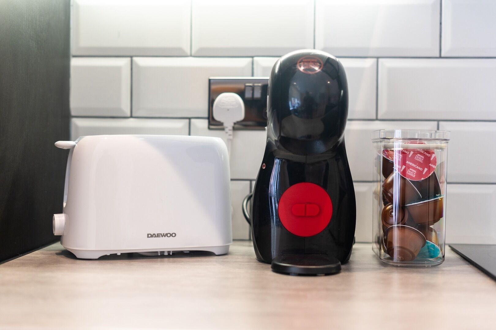 A kitchen with a white toaster, a black coffee maker, and a glass jar with chocolate candies.