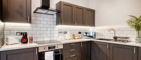 A modern kitchen with dark wooden cabinets, a stainless steel range hood, and a white tiled backsplash.