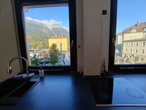 Une pièce avec une fenêtre donnant sur une montagne et un bâtiment jaune.