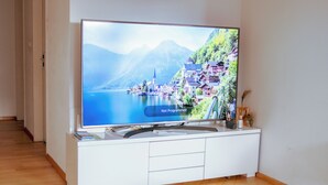 Un téléviseur à écran plat, posé sur un meuble blanc, affiche une image de paysage.