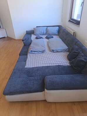 Een moderne woonkamer met een hoekbank, een kamerkleed met dessin en een raam met uitzicht.