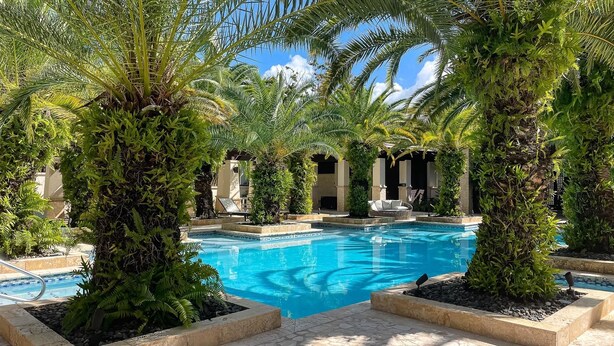 A pool surrounded by palm trees and a stone pathway.