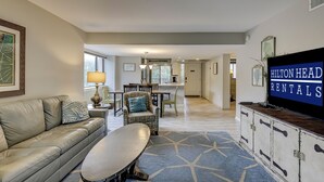 A spacious living room with a leather sofa, a coffee table, and a television displaying 'Hilton Head Rentals'.