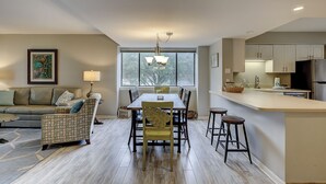 A modern kitchen with a dining area, featuring a wooden table, bar stools, and a built-in refrigerator.