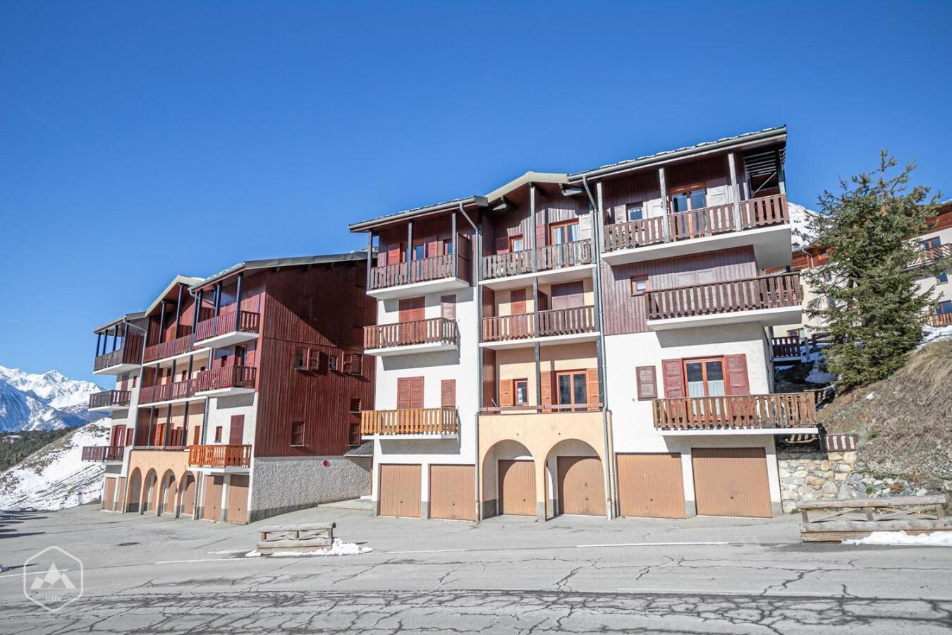 Hotel de diversos pisos amb balcons, façana de pedra i un paisatge de muntanyes al fons.