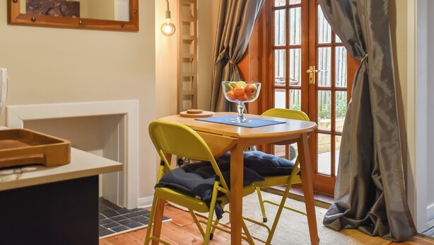 Un coin repas avec une table, des chaises et un panier de fruits.