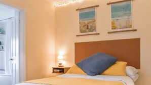 Une chambre à coucher avec un lit, une table de chevet, une lampe et deux tableaux encadrés accrochés au mur.