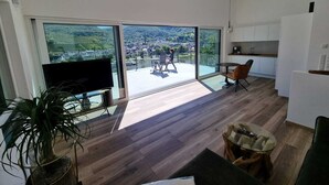 A modern living space with a large sliding glass door leading to a balcony with a scenic view.