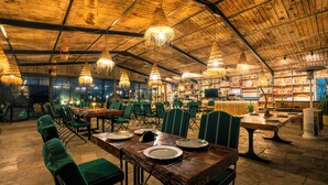 A restaurant with wooden ceiling, hanging lights, green chairs, and tables set for dining. - Bio et bois - Luxury Bio farm (Ain Chkef)