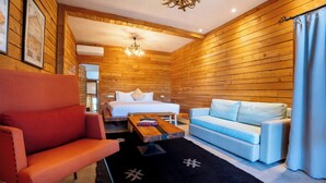 A wooden room with a bed, a red armchair, a light blue sofa, and a wooden coffee table. - Bio et bois - Luxury Bio farm (Ain Chkef)
