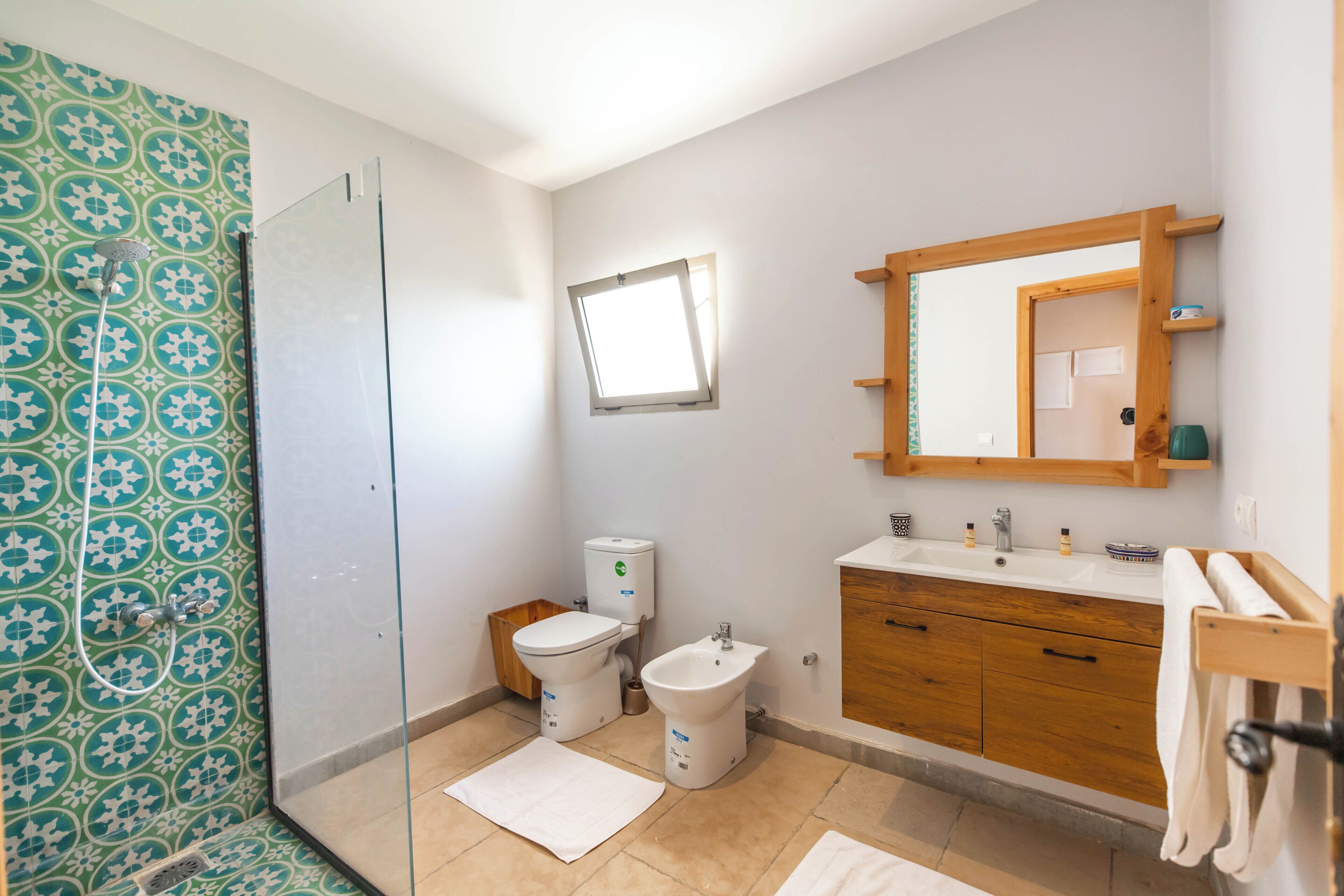 Un baño con ducha, inodoro, bidé, tocador y espejo.