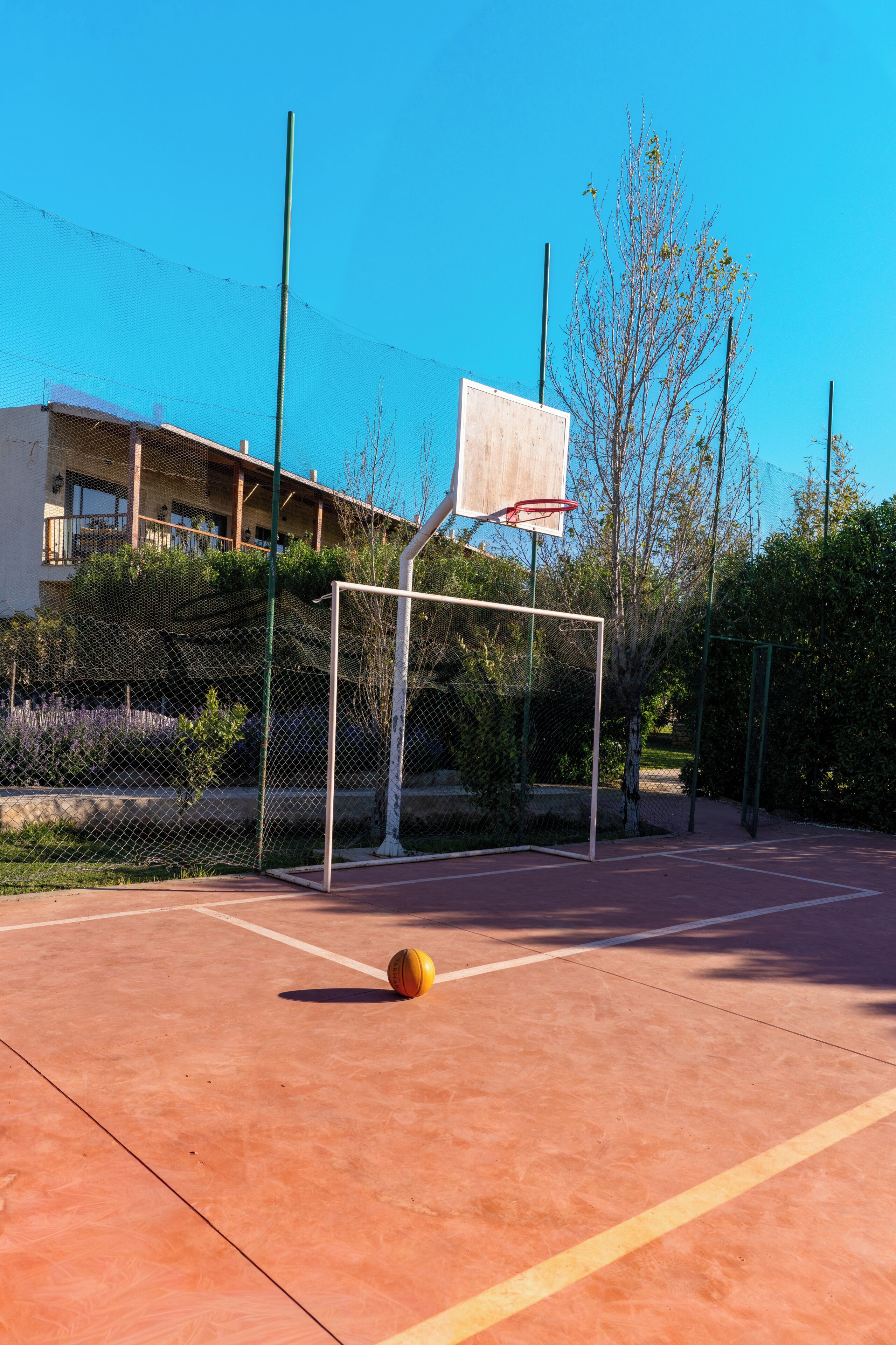 Una cancha de baloncesto al aire libre con un aro, una red y un balón.