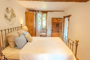 Ein Schlafzimmer mit einem Bett, Kissen, einem Sessel, einer Holztür und einer Wanddekoration.