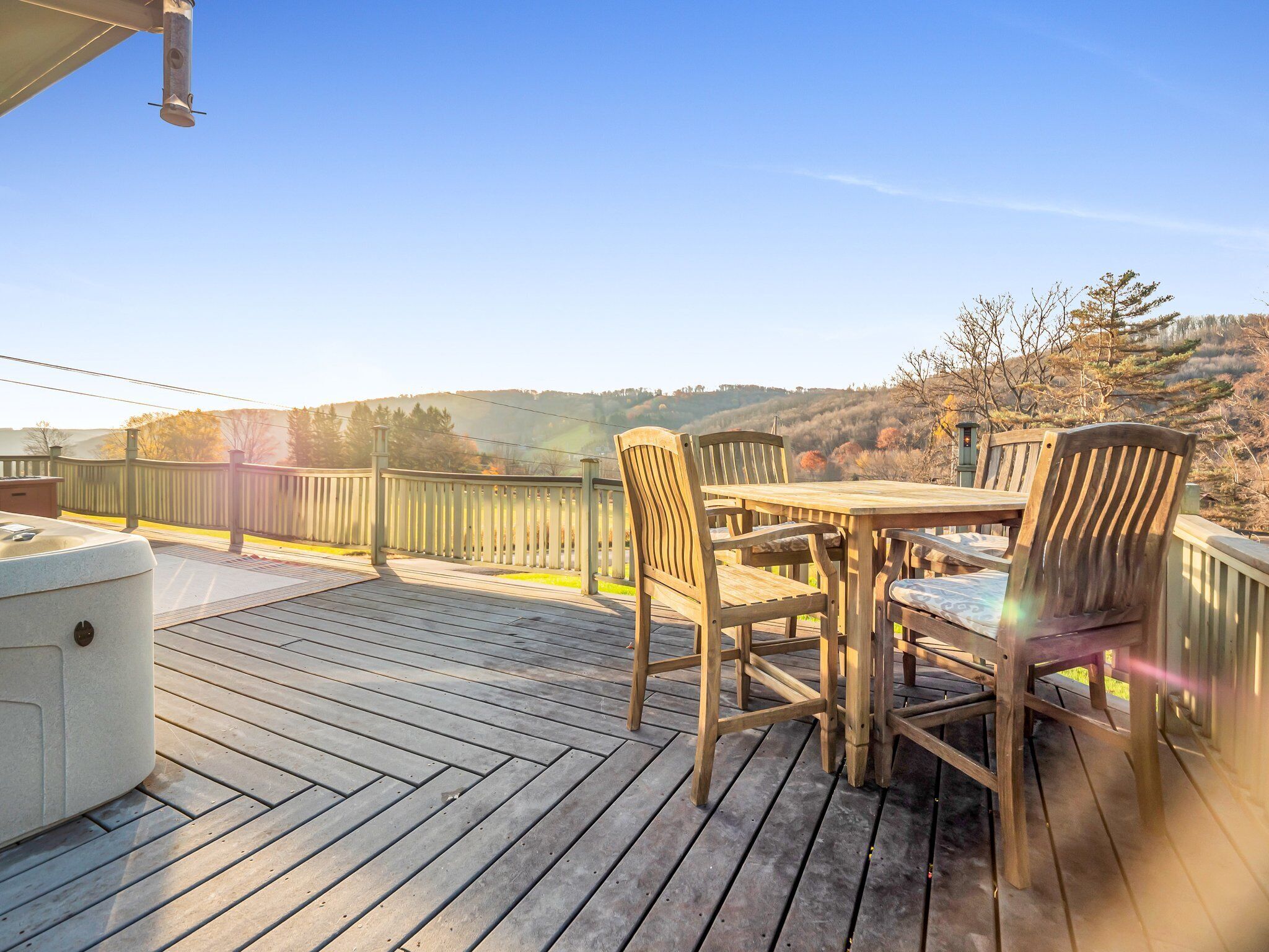 Eine Holzterrasse mit Whirlpool, Holzstühlen und einem Tisch.