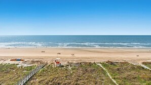 A beach with a lifeguard tower and a wooden walkway leading to the shore. - Windemere 605 -Oceanfront 3BR/2BA-Indoor Pool (North Myrtle Beach)