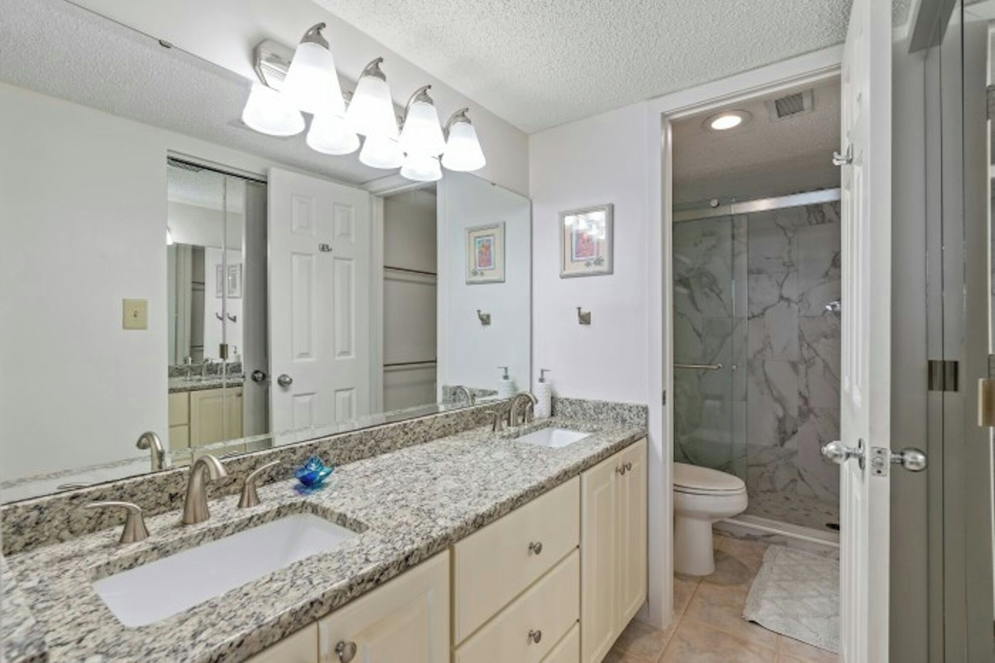 Une salle de bain avec un double lavabo, un grand miroir et un espace douche.