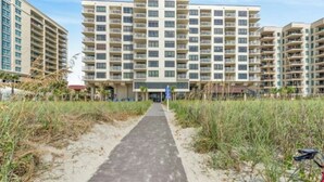 A multi-story hotel with a central entrance and a pathway leading to the building. - Windemere 605 -Oceanfront 3BR/2BA-Indoor Pool (North Myrtle Beach)