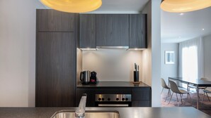 A modern kitchen with dark wood cabinets, stainless steel appliances, and a central island with a sink. - Modern City Apartments (Interlaken)