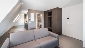 A modern living room with a grey sofa, a wooden cabinet, and a white door. - Modern City Apartments (Interlaken)