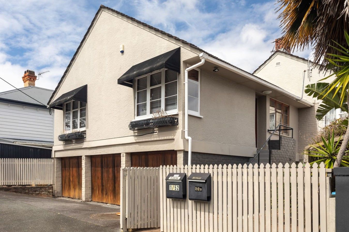 Une maison à deux étages avec un garage, une clôture en piquets et des boîtes aux lettres.