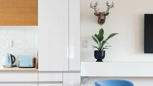 A modern kitchen with white cabinets, a blue chair, a mounted deer head, and a potted plant. - 2-bed apartment in the heart of Ponsonby (Auckland)
