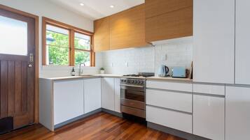 A modern kitchen with white cabinets, a wooden door, and a window.