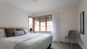 A bedroom with a bed, a chair, a window with blinds, and a framed picture on the wall. - 2-bed apartment in the heart of Ponsonby (Auckland)