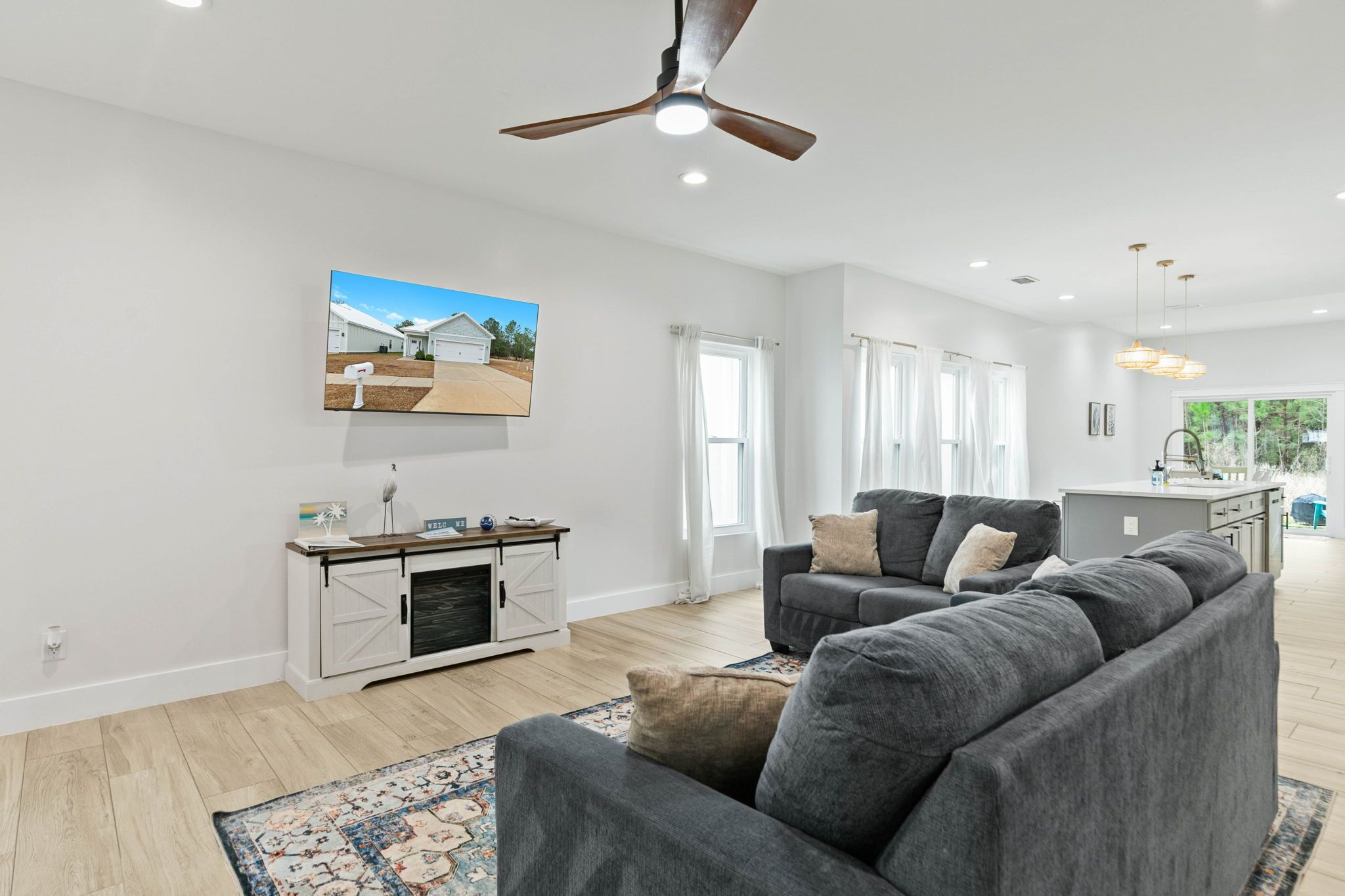 A spacious living room with a gray sectional sofa, a wooden coffee table, and a ceiling fan.