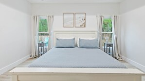 A bedroom with a large bed, two bedside tables, a nightstand, and a window with curtains. - Family home near OWA, beaches. King bed, cornhole, fire pit, pet friendly! (Foley)