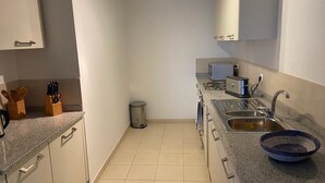 A compact kitchen with a microwave, toaster, and sink. There are cabinets and a trash can. - Tortuga/3beds/pool/tv/wifi (Sal)