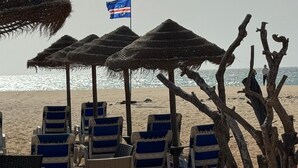 Beach chairs under thatched umbrellas, a flag, and driftwood. - Tortuga/3beds/pool/tv/wifi (Sal)