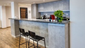 A modern kitchen with a granite countertop, bar stools, and a potted plant. - Prime Select Old Cairo Nile View (Cairo)