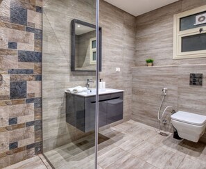 Ein modernes Badezimmer mit einer Duschkabine aus Glas, einem Waschtisch mit Spüle und einer Toilette.