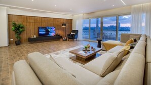 A modern living room with a large flat-screen TV, comfortable seating, and a balcony with a city view. - Prime Select Old Cairo Nile View (Cairo)
