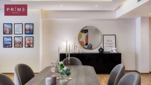 A modern dining area with a wooden table, grey upholstered chairs, and a black console table with candles and a framed quote. - Prime Select Old Cairo Nile View (Cairo)