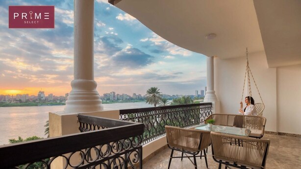 A balcony with a view of a river and city skyline at sunset. - Prime Select Old Cairo Nile View (Cairo)