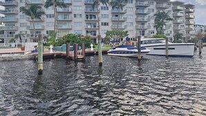 A waterfront property with a marina, modern buildings with balconies, and palm trees.