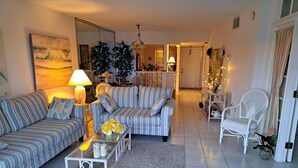 A living room with striped sofas, a glass coffee table, and a white chair.