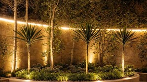 A landscaped outdoor area with a curved stone wall, palm trees, and a stone floor. - Sol Pyramid Inn (Giza)