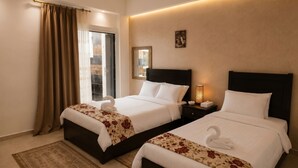 A hotel room with two beds, a nightstand with a lamp, a window with curtains, and a wall-mounted picture. - Sol Pyramid Inn (Giza)