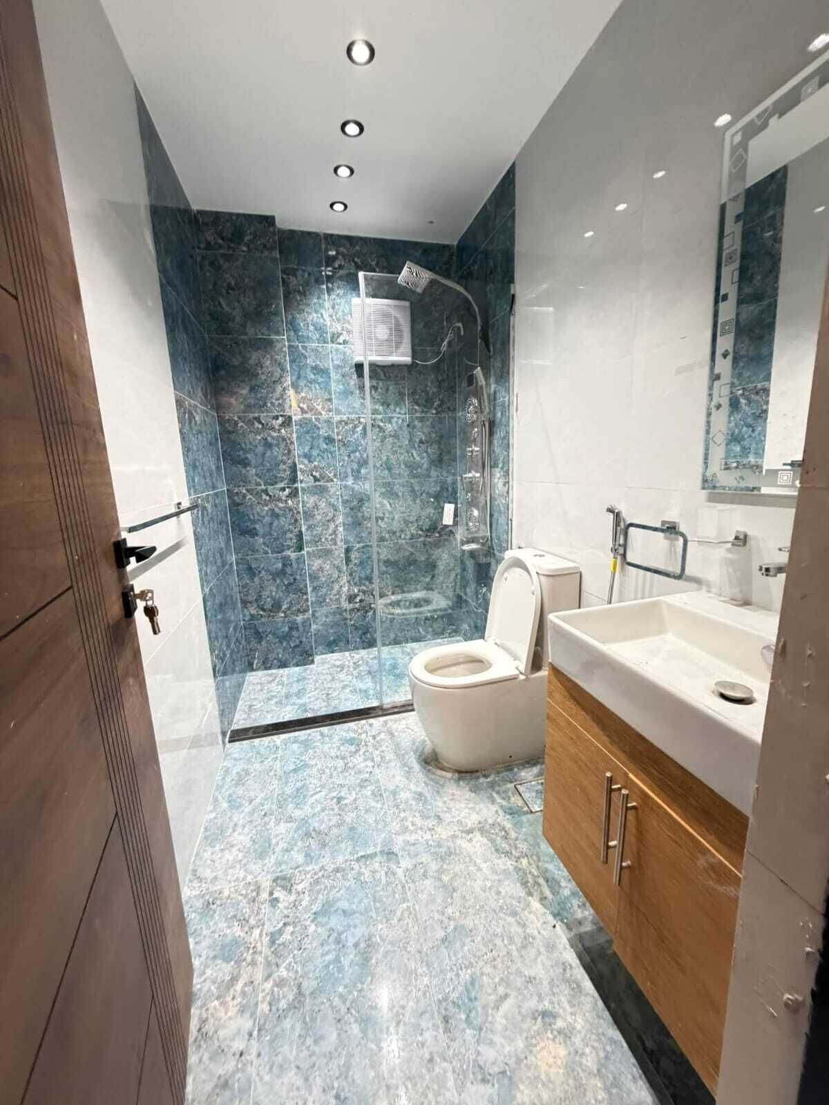 A modern bathroom with a shower, toilet, and vanity.