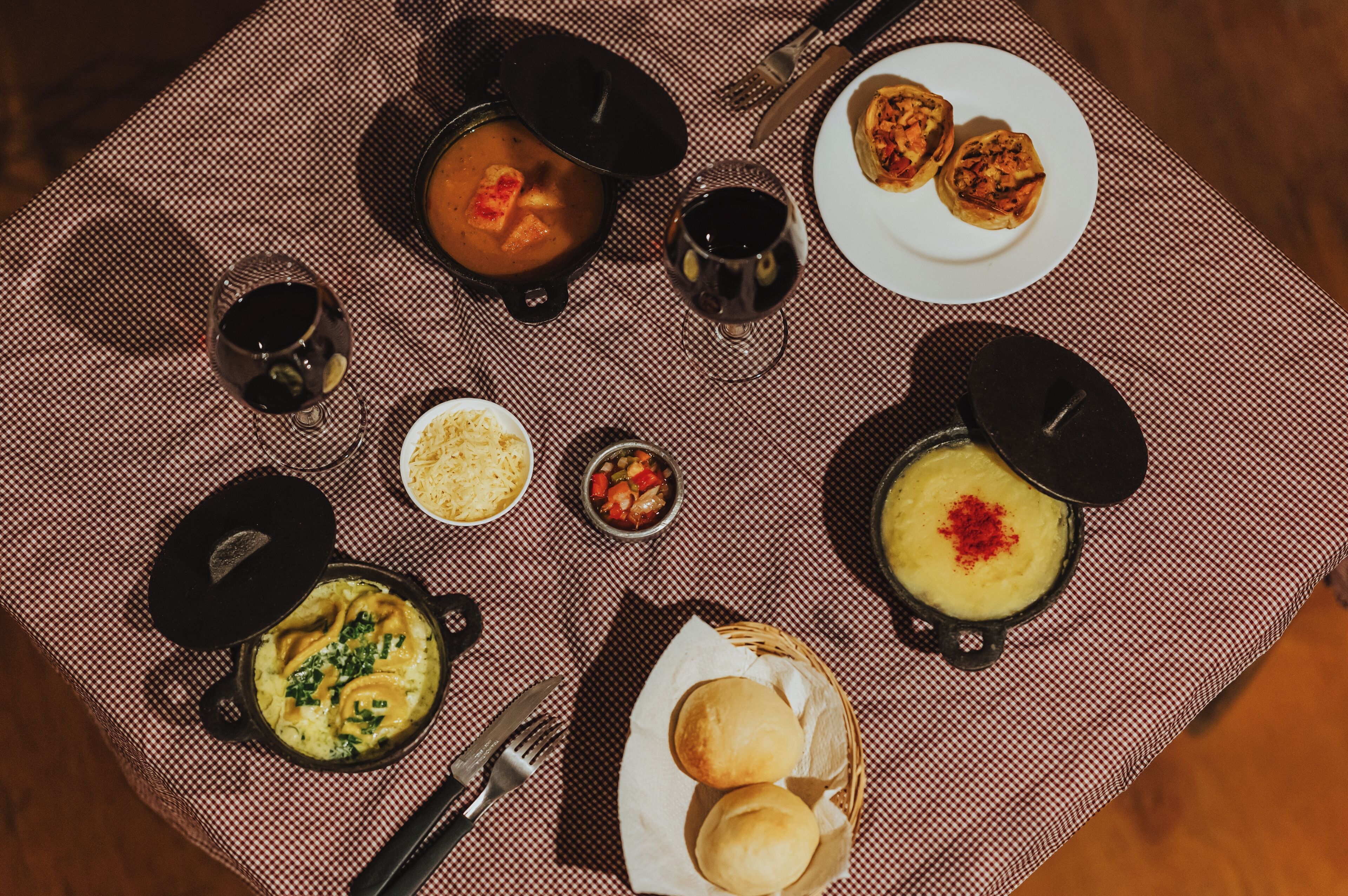 Een tafel gedekt met diverse gerechten, waaronder soep, brood en een kleine schaal groenten.