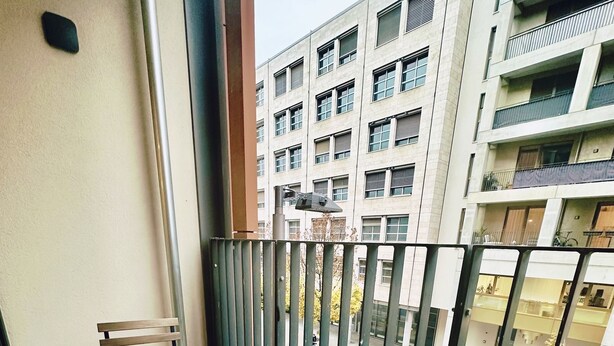 A balcony with a wooden table and chairs, a metal railing, and a view of a multi-story building with balconies. - Most popular apartment in the center (Dresden)