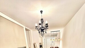 A modern living room with a flat-screen TV on a wooden stand, a green sofa, a wooden coffee table, and a chandelier. - Most popular apartment in the center (Dresden)